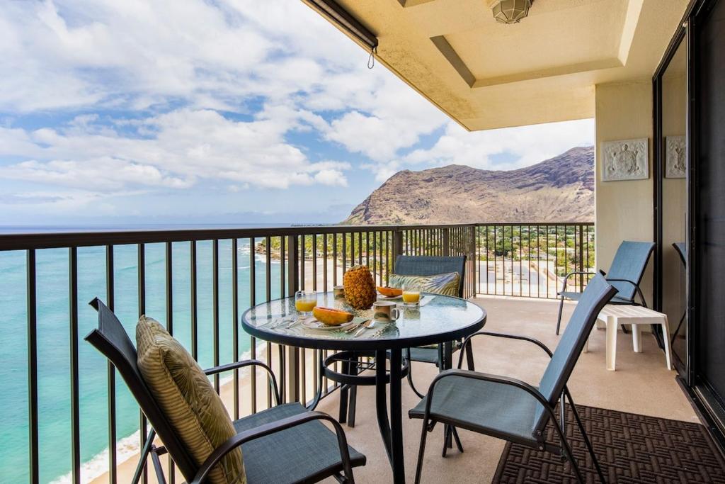 a balcony with a table and chairs and the ocean at Oceanfront Corner Unit , Hawaiian Princess in Waianae