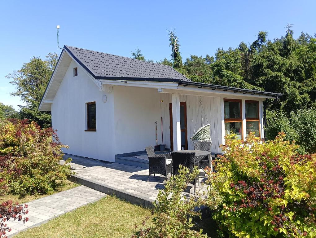 a small white house with a porch and some bushes at Budlejowy domek in Kołczewo