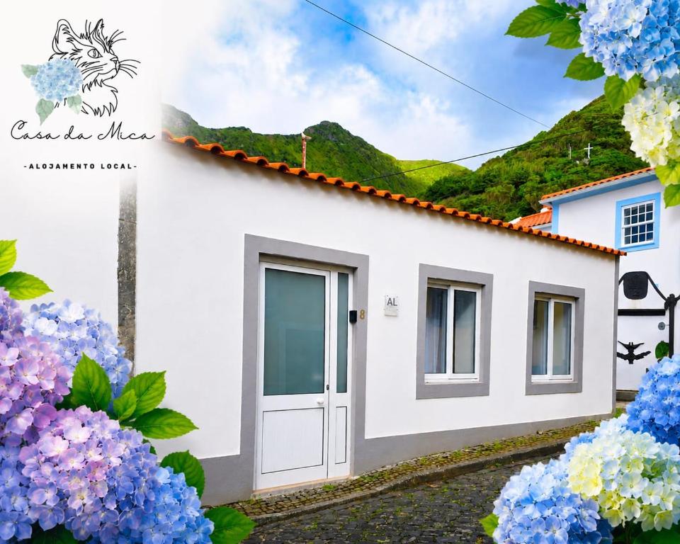 a white house with blue flowers in front of it at Casa da Mica in Faja Grande