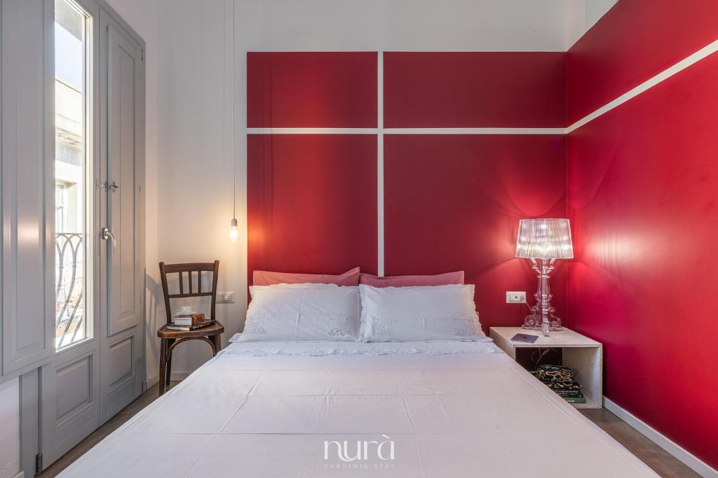 a bedroom with a red wall and a bed at Wine Passion Room in Quartu SantʼElena