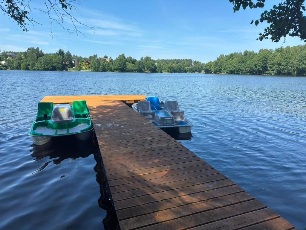 two boats sitting on a dock on a lake at Domek na Kaszubach nad jeziorem Kamień - Prywatne Jacuzzi i Rowerek Wodny in Kamień