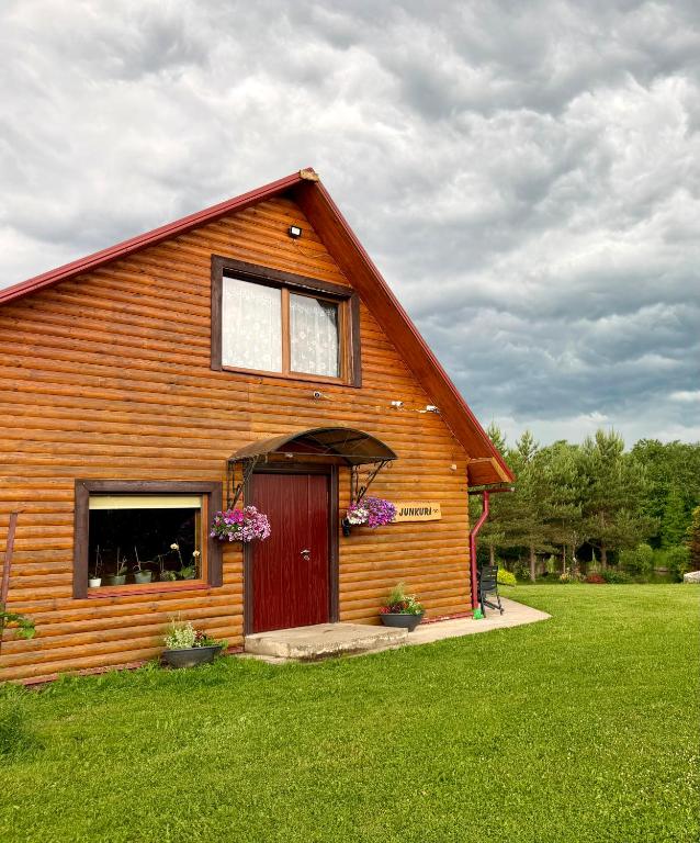 a wooden barn with a red door on a green field at Junkuri Holiday House 9 Beds up to 20 Guests in Jeroškina