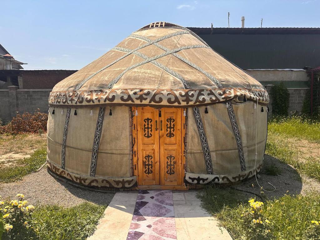 a large yurt with a wooden door in a yard at Yurt guesthouse in Osh