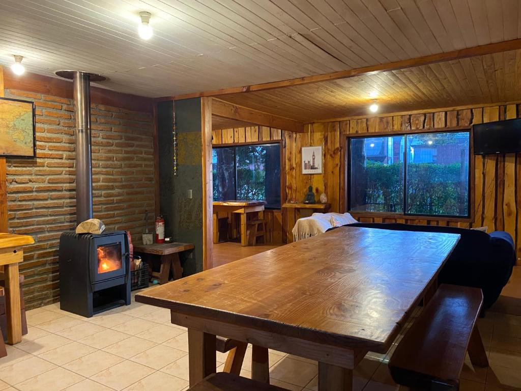 a room with a wooden table and a wood stove at Hostel Raíz Del Pillán in Pucón
