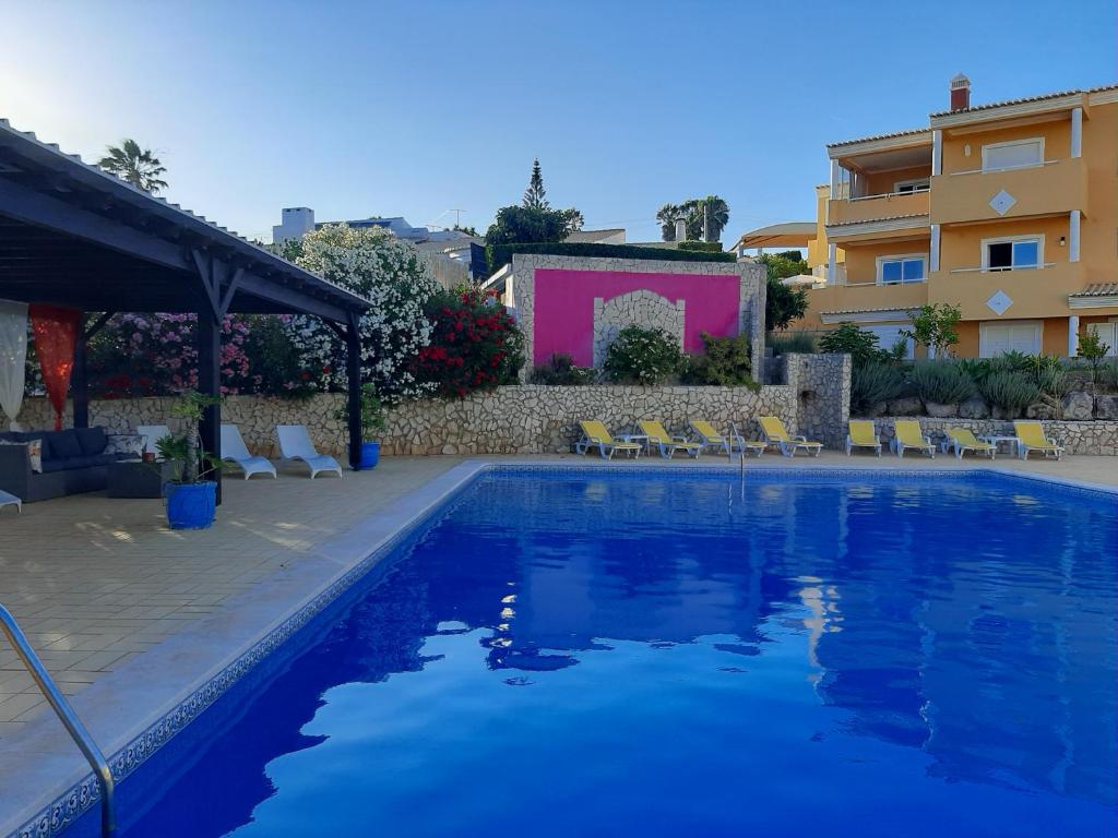a swimming pool with chairs and a building at Lucie Lime GuestHouse in Luz