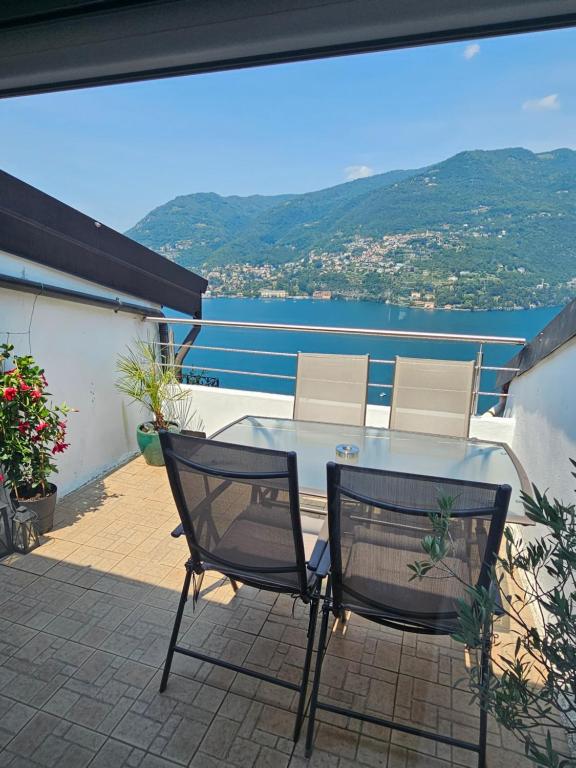 a table and chairs on a balcony with a view of the water at Vista Lago Como con terrazza in Blevio