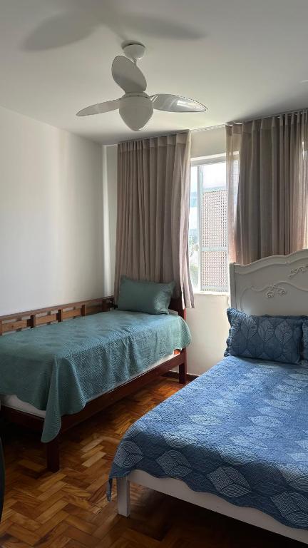 a bedroom with two beds and a ceiling fan at Quarto privativo confortável próximo a ufba, praia, comercio e zoológico in Salvador