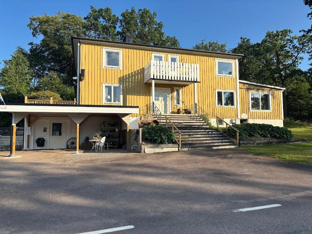 a large yellow house with stairs and a porch at Bergåsa bed & kitchen Drängsered in Torup