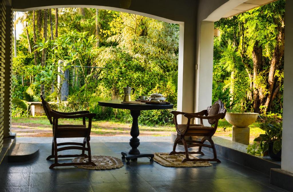a patio with a table and two chairs and a table at Luminosium Nature Retreat & Heritage Forest Garden in Pannala