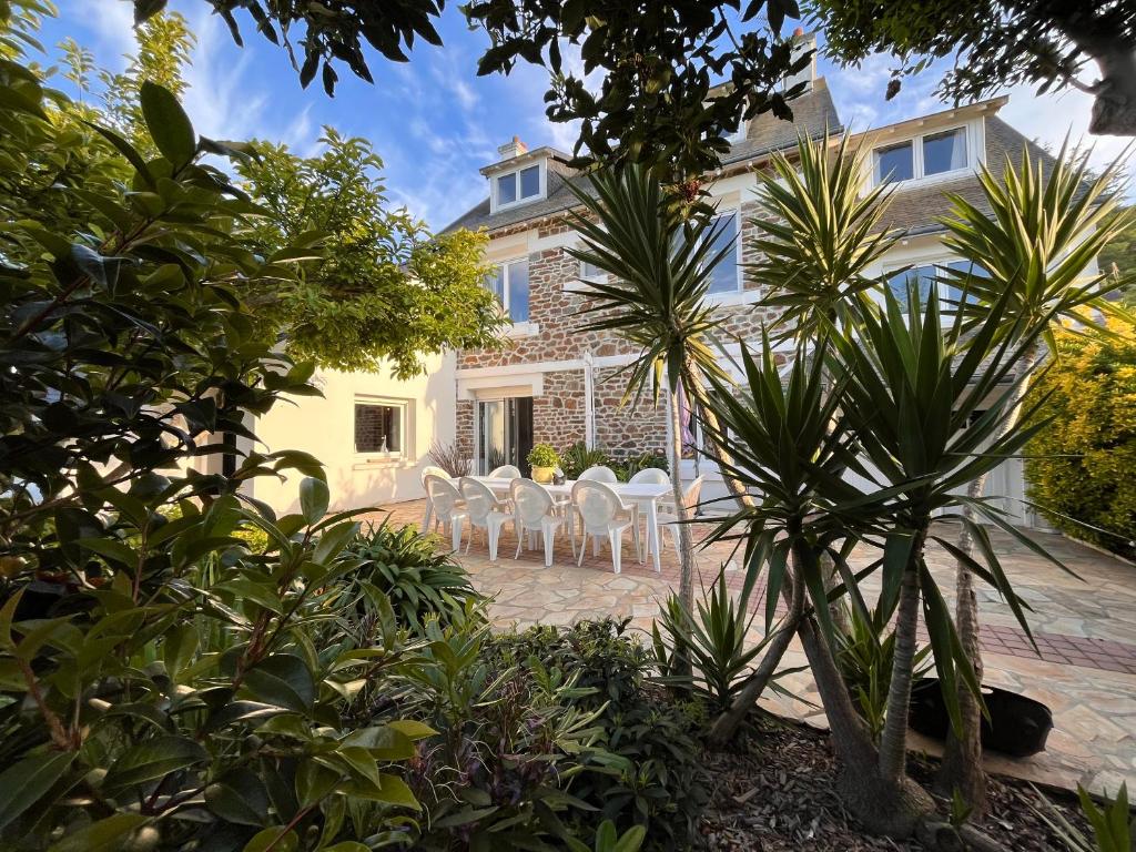 a patio with white chairs in front of a house at La petite duchesse - jaccuzzi in Plérin