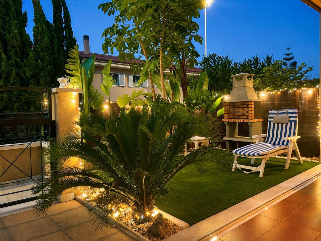 a patio with a chair and a palm tree and lights at Bungalow with Pool & BBQ - Carabassi Beach 10' in Gran Alacant