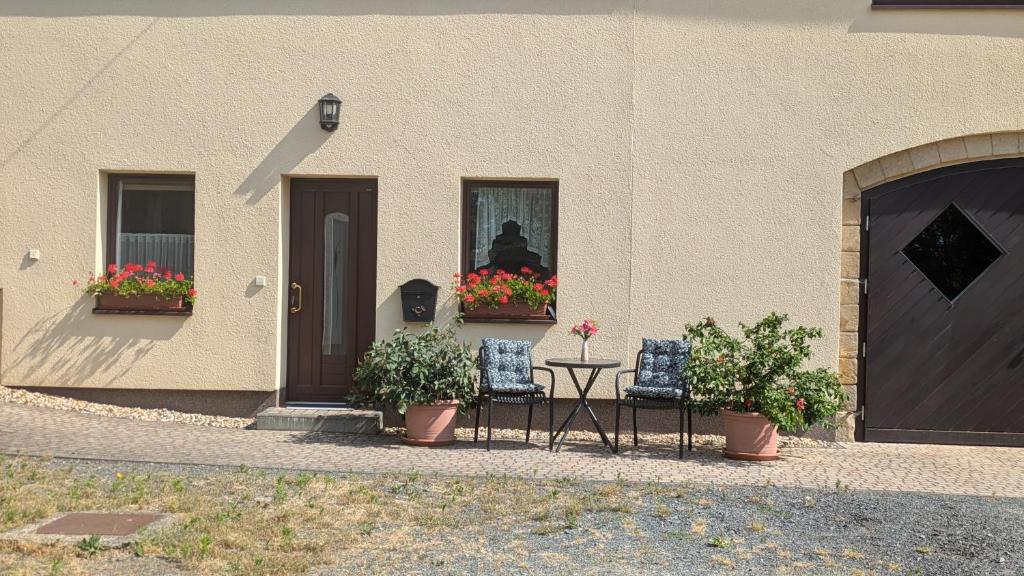 a building with two chairs and a table and flowers in a window at Ferienwohnung Marks - Hohnstein in Rathewalde