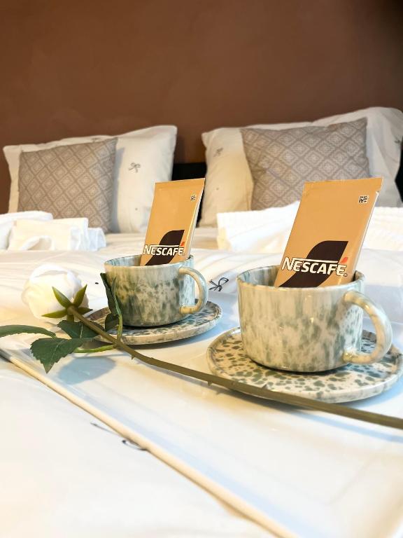 two tea cups on a bed with certificates on them at Brightside Suite in Kristiansand