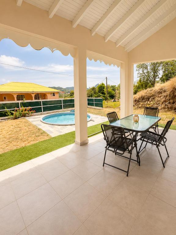 a patio with a table and chairs and a pool at Les Cocons des Alizés in Sainte-Anne