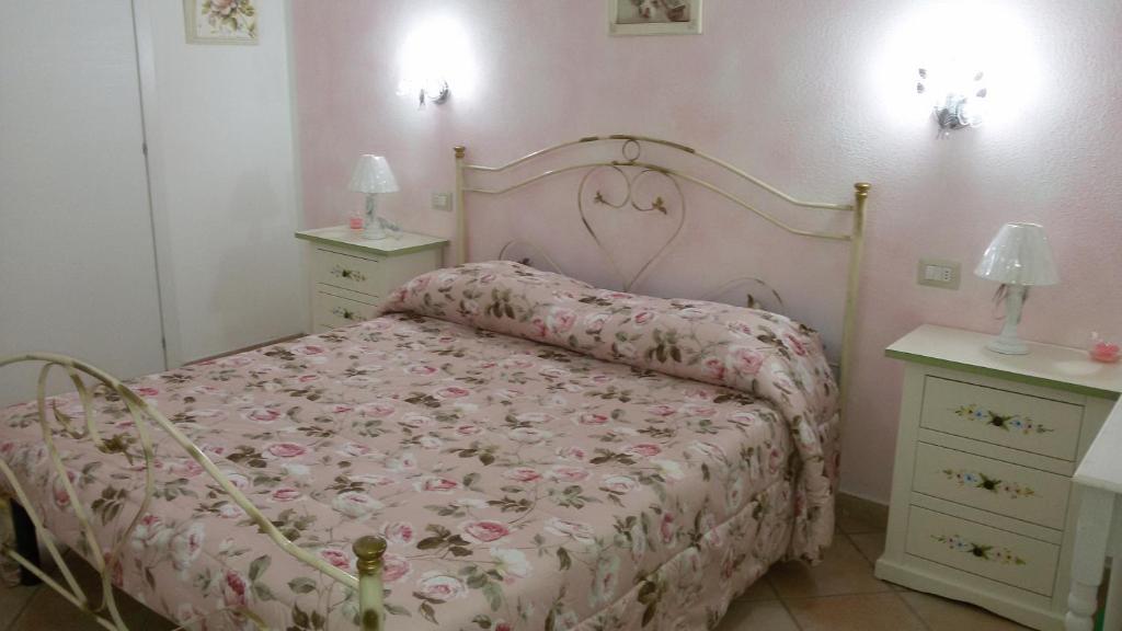 una camera da letto con un letto con copriletto rosa e 2 comodini di B&B Le Rose a Olbia