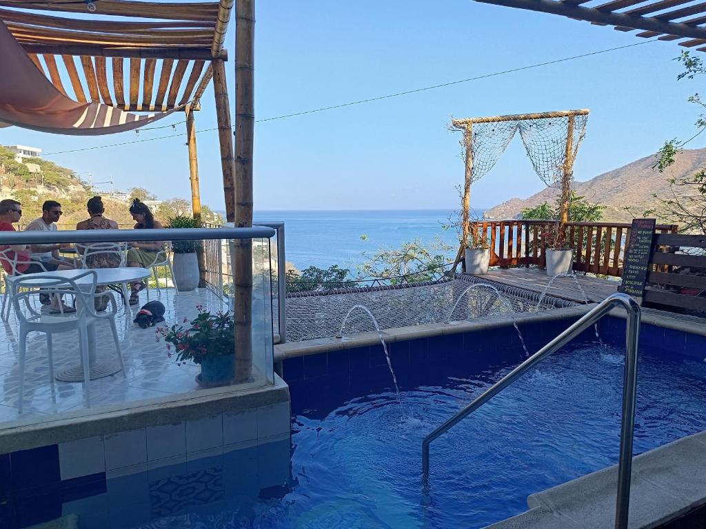 a plunge pool with people sitting at a table and the ocean at Tayrona Colors Hostel in Taganga