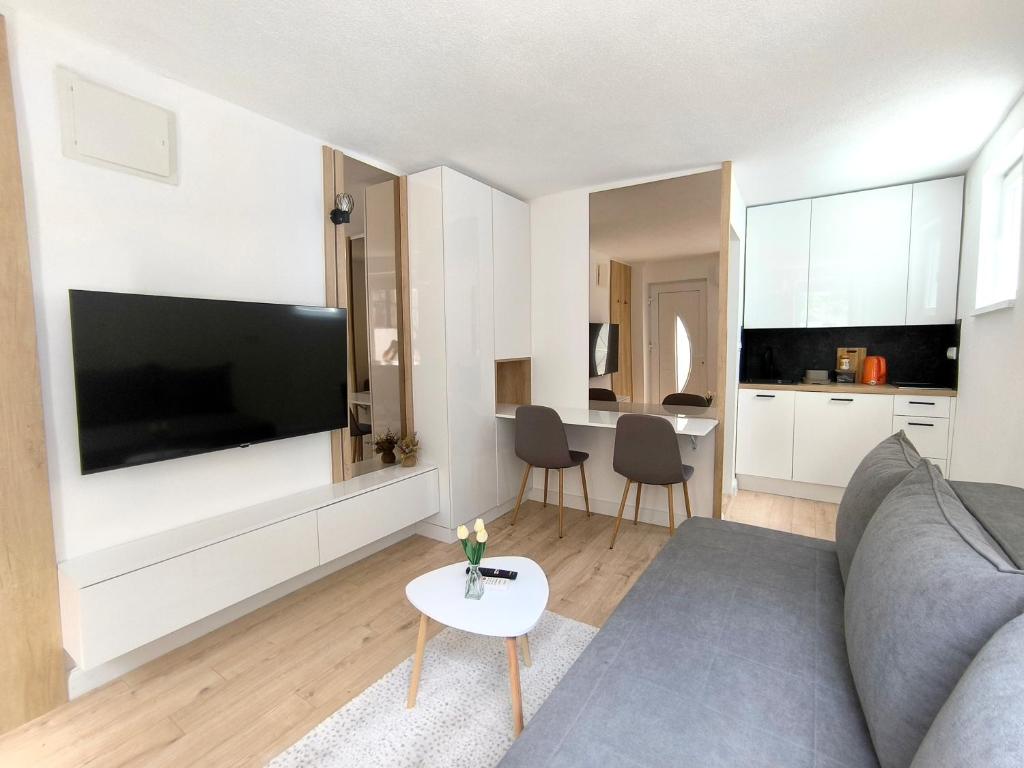 a living room with a couch and a tv and a table at El Higo Apartments in Mostar