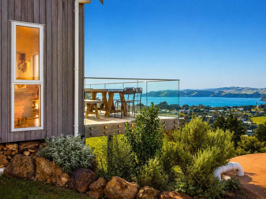 a house with a balcony with a view of the water at Overview - Stay Waiheke in Ostend