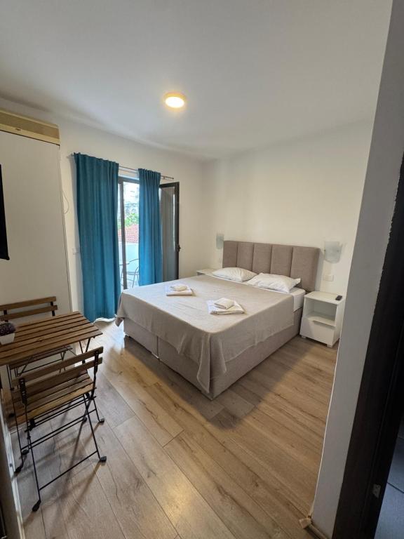 a bedroom with a bed and a table and blue curtains at Guest house Mia Becici - Sobe i Apartmani in Budva