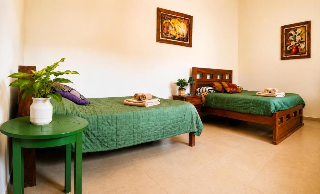ein Schlafzimmer mit zwei Betten und einem Tisch mit einem grünen Bett in der Unterkunft Looking Samaipata in Samaipata
