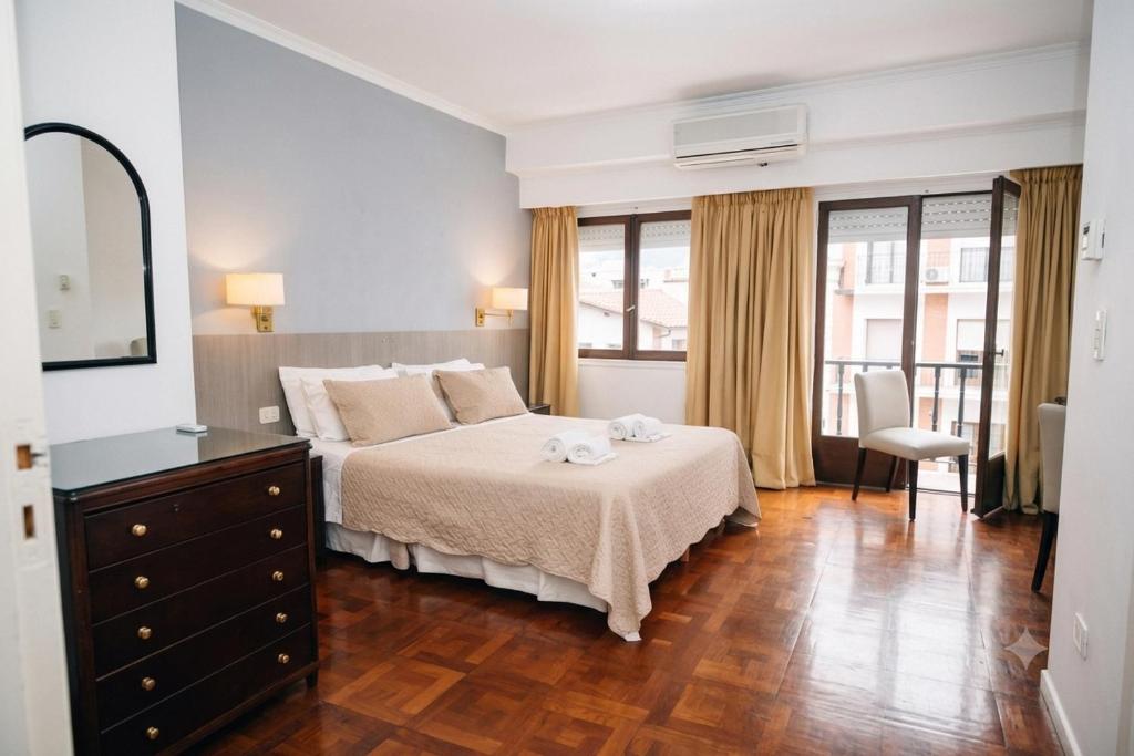 a bedroom with a bed with a dresser and a mirror at Gran Hotel Miglierina in Mar del Plata