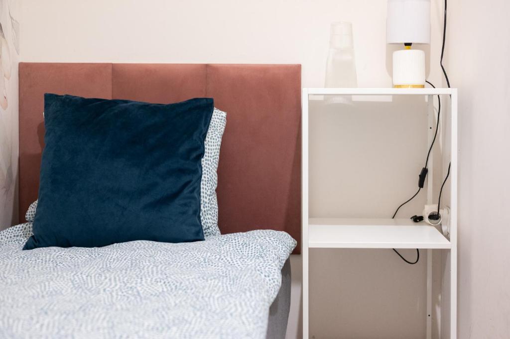 a bed with a blue pillow and a white shelf at S-HE Space - Budget Micro Rooms Kraków in Krakow