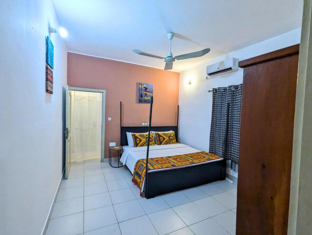 a bedroom with a bed in a room at Petit Cocon de Ouidah - Chambre Cosy Climatisée - Plage a 10 min - Salon, Cuisine et balcon in Ouidah