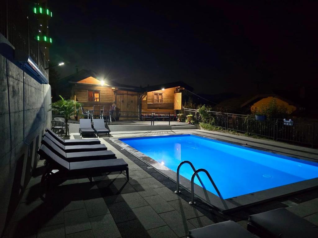 a swimming pool at night with two lounge chairs next to it at Azure Pool Residence in Sarajevo