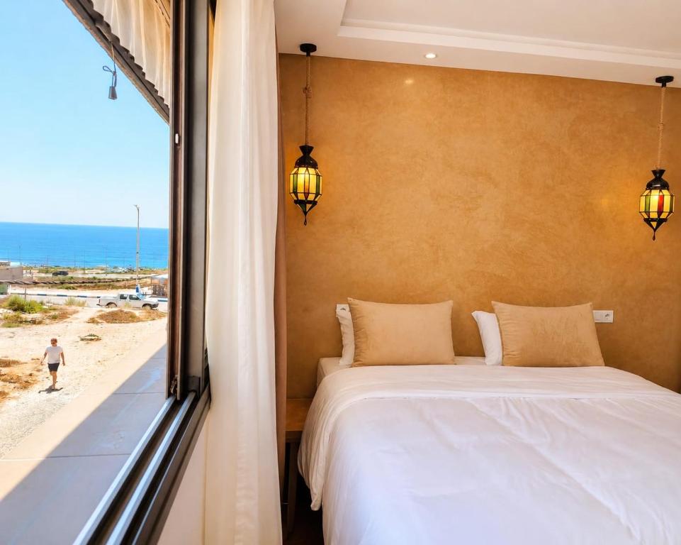 a bedroom with a bed and a view of the beach at Dar-Vida Guesthouse in Imsouane
