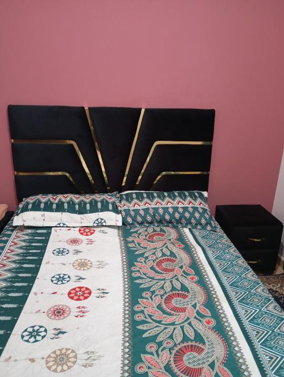 a bed with a black head board with a quilt on it at Asrati in Ifrane