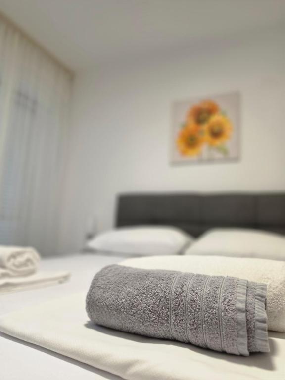 a white bed with a towel on top of it at Apartmani Morѐll in Novalja