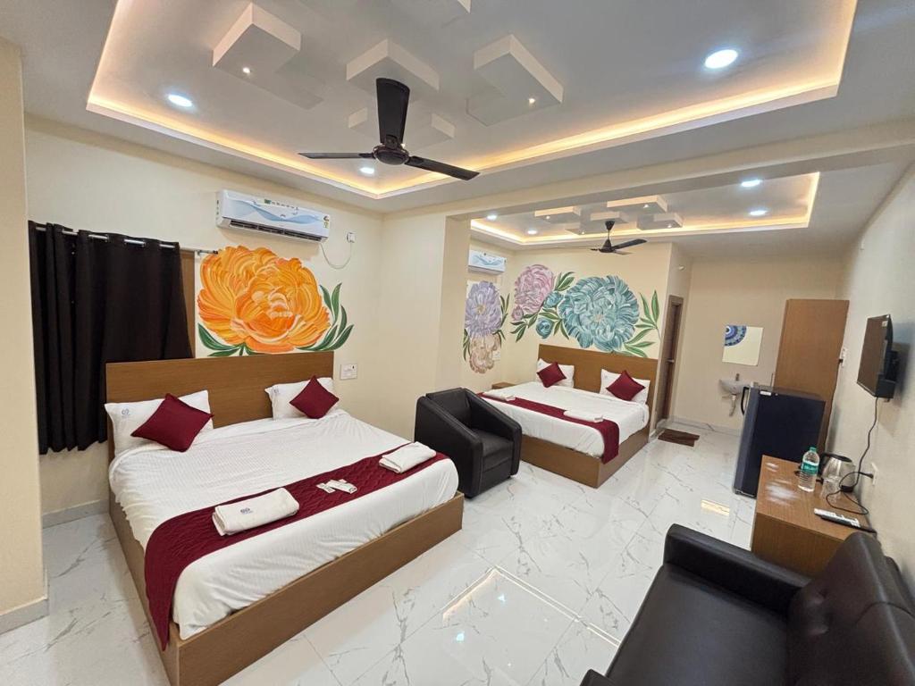 a bedroom with two beds and a desk and a tv at Jay & Jas Hotel in Tirupati