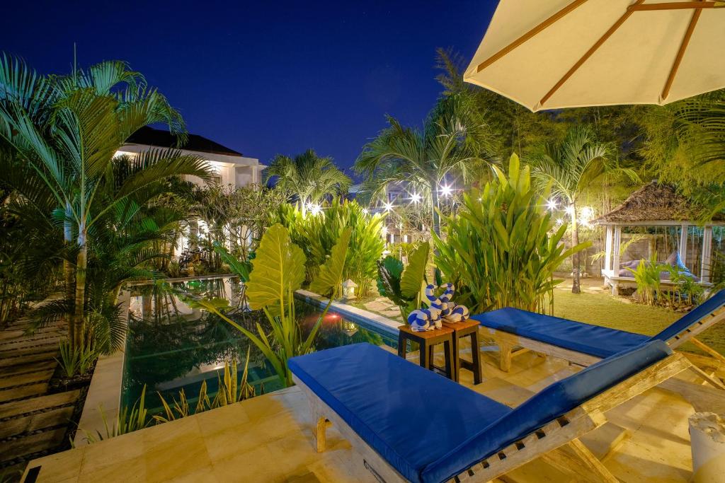 an outdoor patio with blue chairs and an umbrella at Drift Hideaway- Adult only in Kuta Lombok