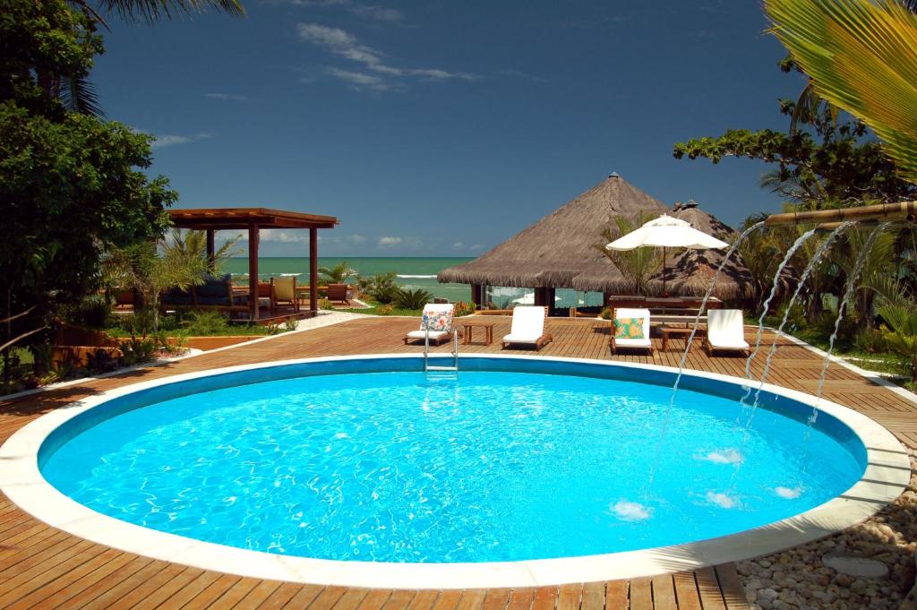 a pool at a resort with chairs and an umbrella at Hotel Pousada Pitinga in Arraial d'Ajuda