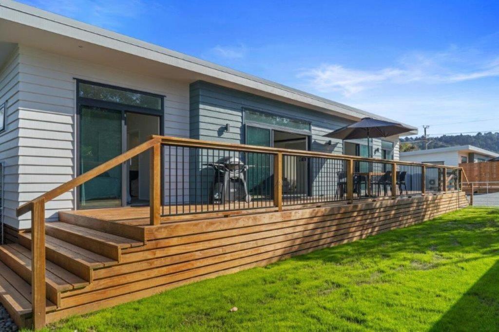 a house with a wooden deck with a patio at Recline on Leo in Waihi Beach