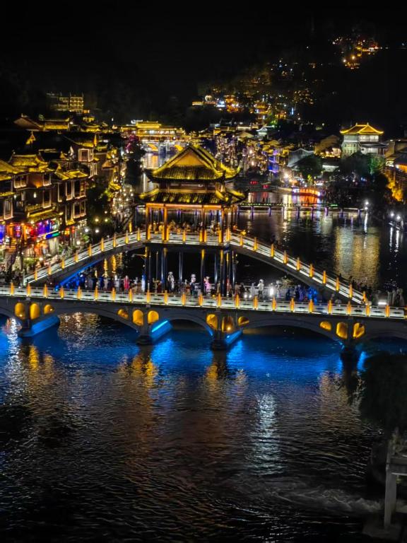 a bridge over a river with a city at night at First encounter with a homestay in Fenghuang County