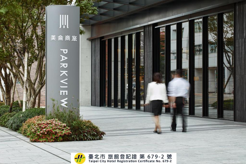 two people walking in front of a building at Parkview Taipei in Taipei