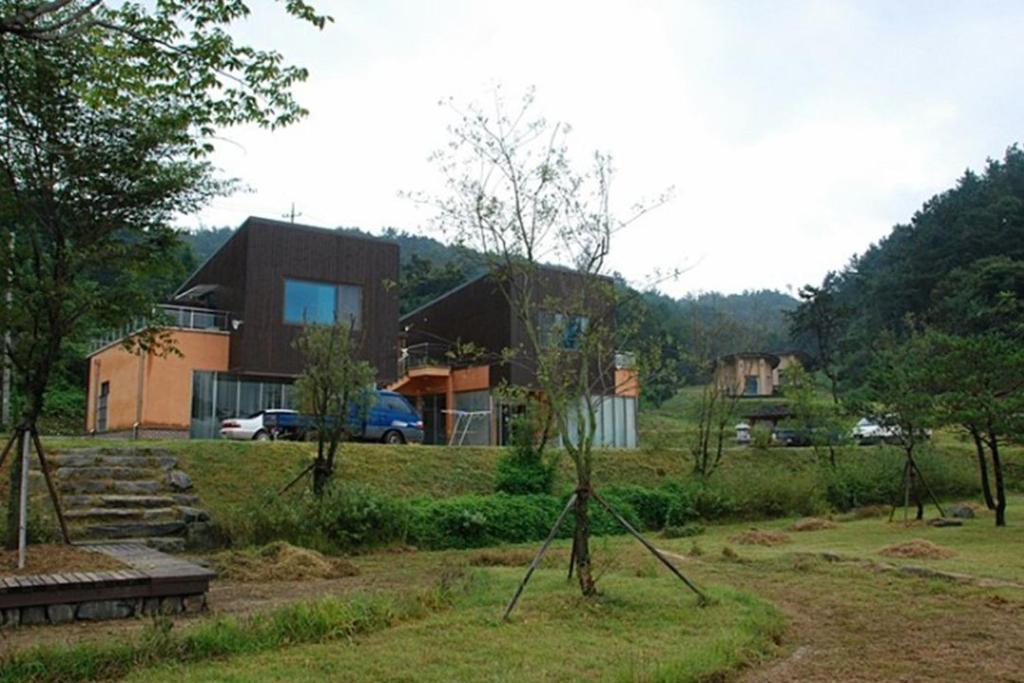 a house in the middle of a yard with trees at Seocheon Water Willow Pension in Seocheon