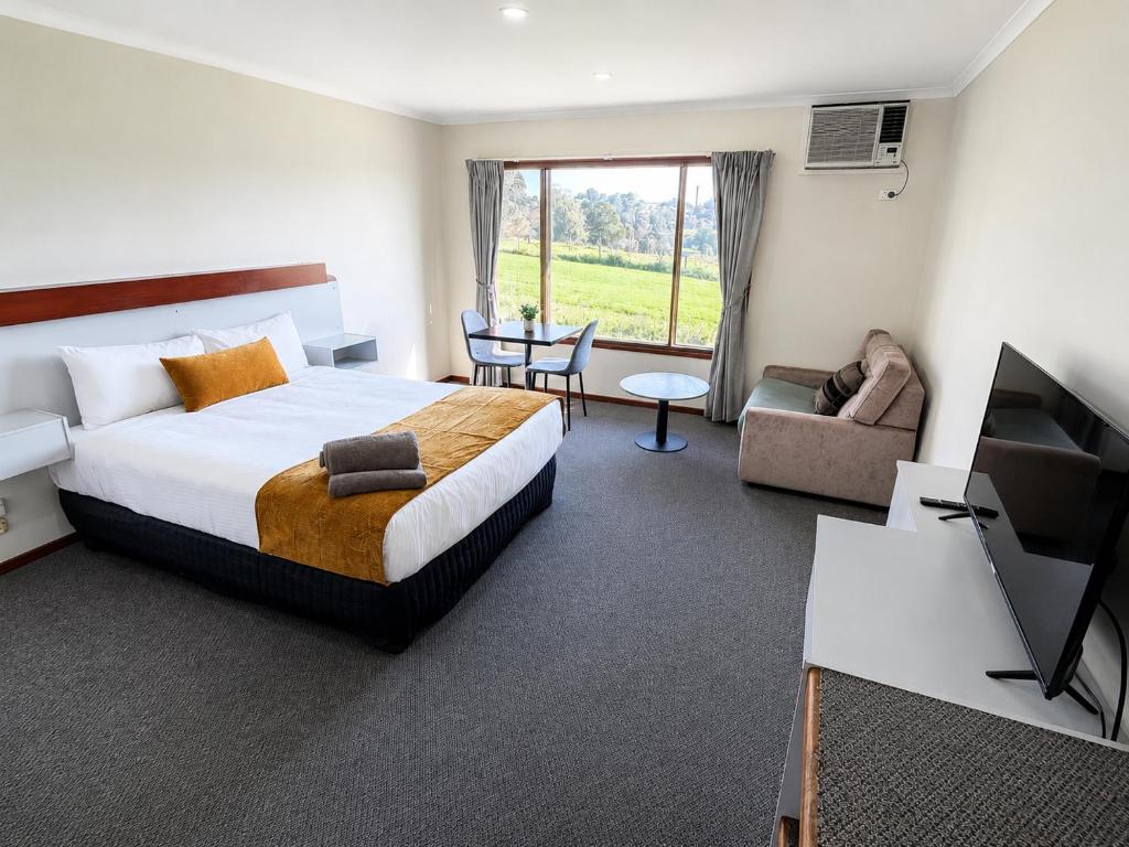a hotel room with a large bed and a tv at Warragul Views Motor Inn in Warragul
