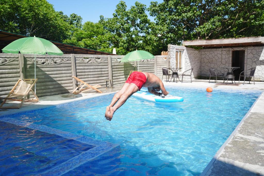 a man laying on aogie board in a swimming pool at Guest House on Rustaveli 176 in Kobuleti