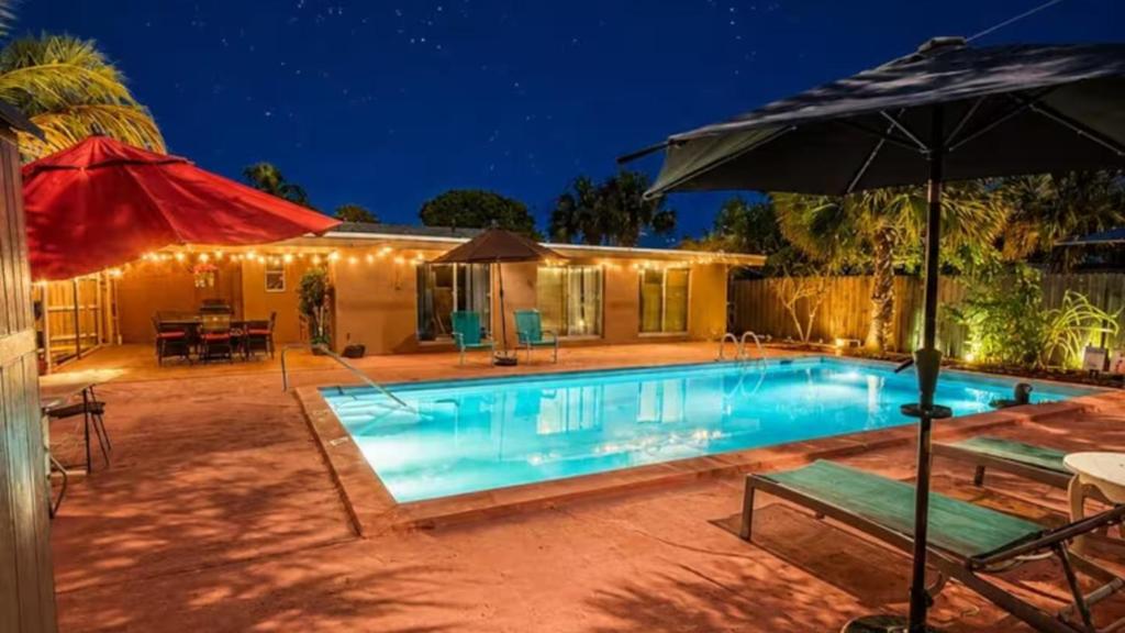 a swimming pool with an umbrella and a house at One-Bedroom Suite Pool with Bath Kitchen in West Palm Beach in West Palm Beach