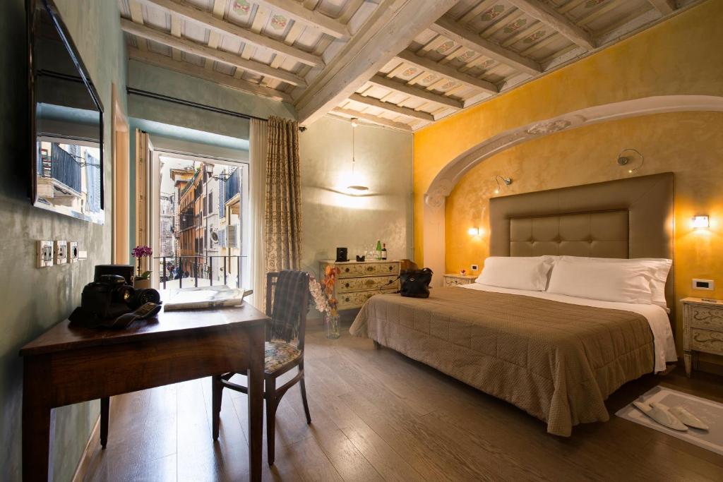 a bedroom with a bed and a desk and a window at Relais Maddalena in Rome