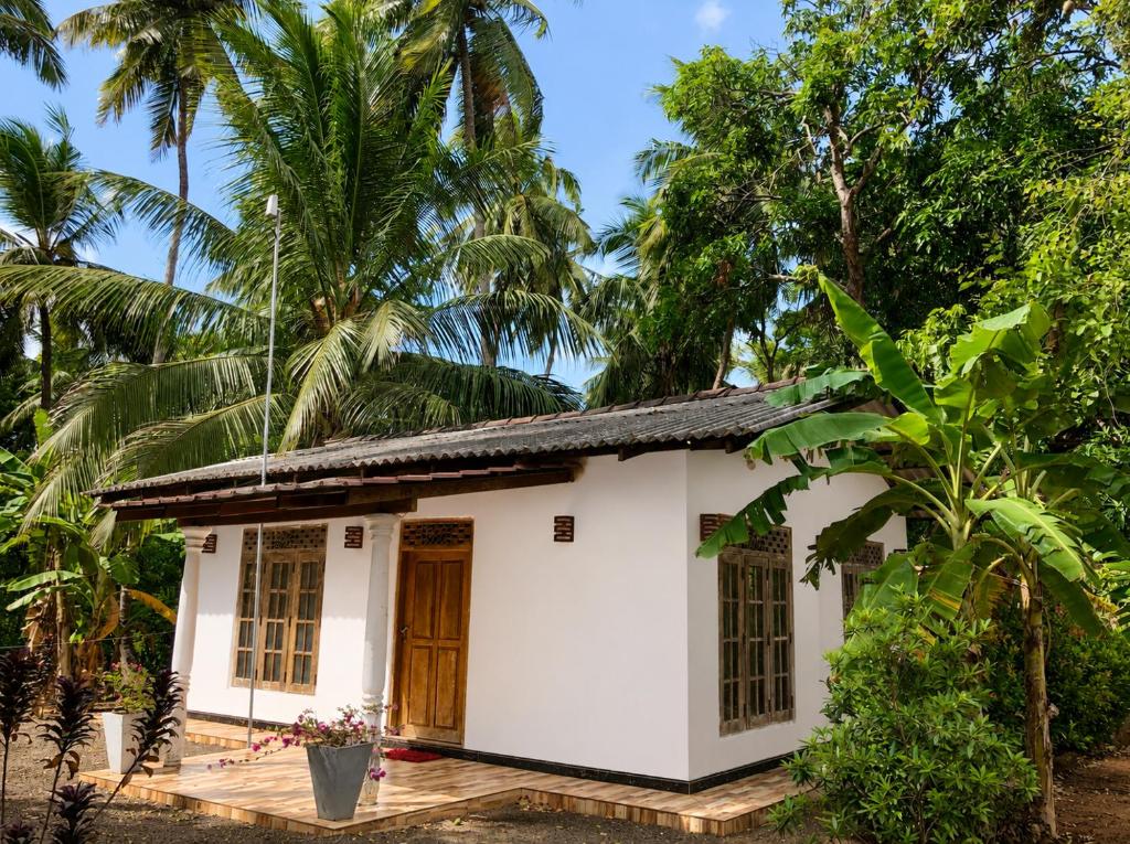 a small white house with palm trees in the background at MG Home Sigiriya in Inamaluwa