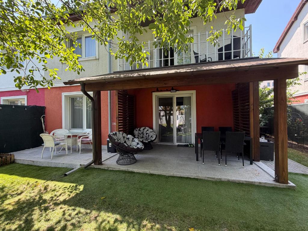 a patio with chairs and a table in front of a house at Elegant Garden Villa American Village Pipera in Voluntari