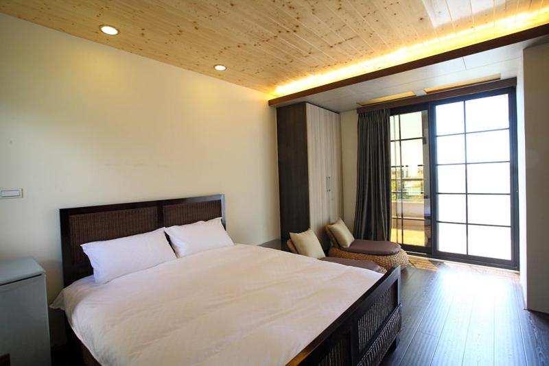 Sung-Ding Guesthouse في جيان: غرفة نوم بسرير ابيض كبير ونافذة