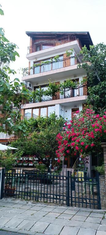 a building with pink flowers in front of a fence at Nirvana Guest House in Nesebar