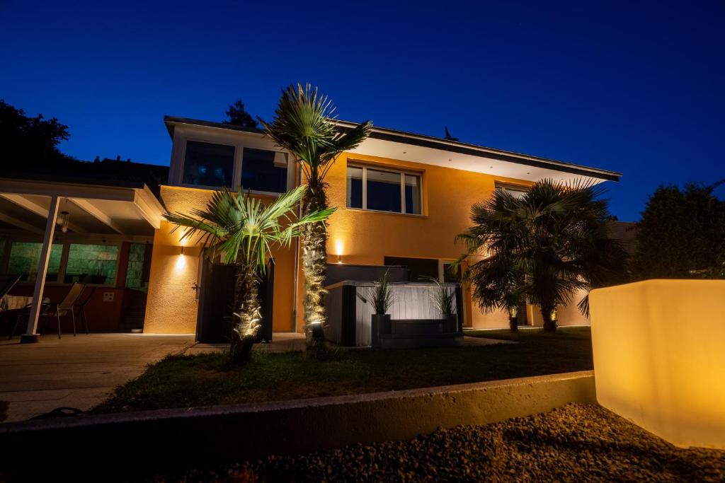 a house with palm trees in front of it at night at Residenza San Remy Hundefreundliche Ferienwohnung mit Whirlpool in Unterkulm