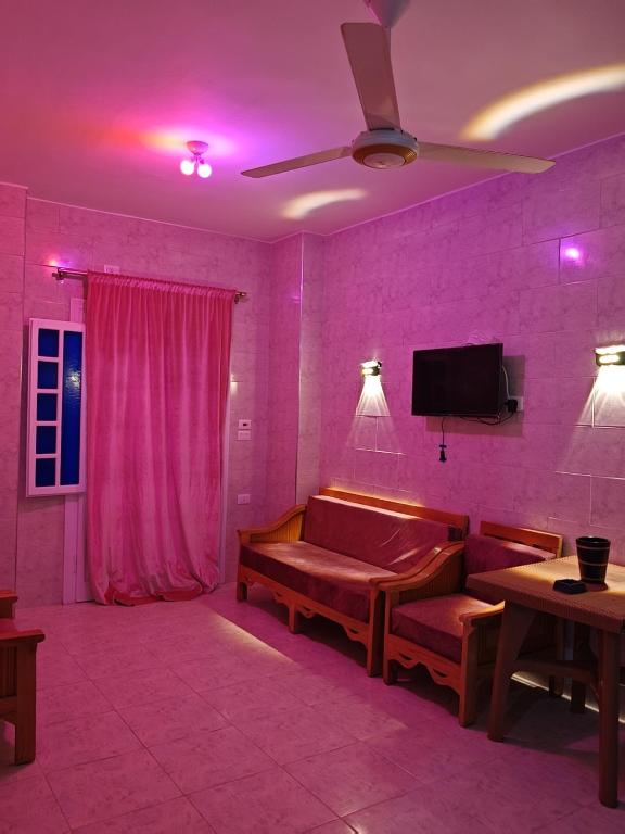 a living room with a couch and a pink wall at See you soon blue Beach in Marsa Matruh