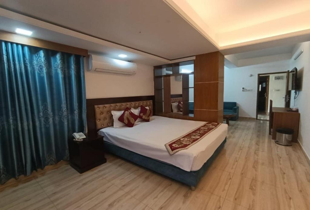 a bedroom with a large bed and a large window at Hotel D Palace in Dhaka