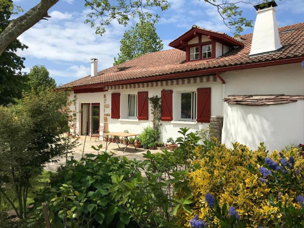 ein Haus mit roten Fensterläden in einem Garten in der Unterkunft Burkia in Sare